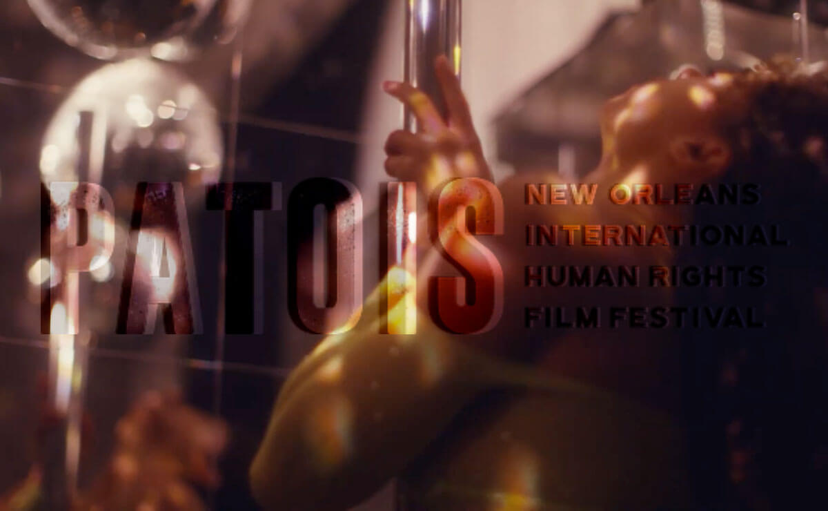 A woman in a yellow dress grips a chrome dance pole and throws her head back as she dances. The image is hazy and, except for the hand on the pole, almost entirely blurred. The woman is mostly in shadow, with patches of dappled golden sunlight illuminating her face and arm. Superimposed over the left and center part of this image is the word "PATOIS" in all caps. To the right of that, in much small capital letters and spread across four lines that together equal the height of "patois," is the festival  name, "New Orleans International Human Rights Film Festival."