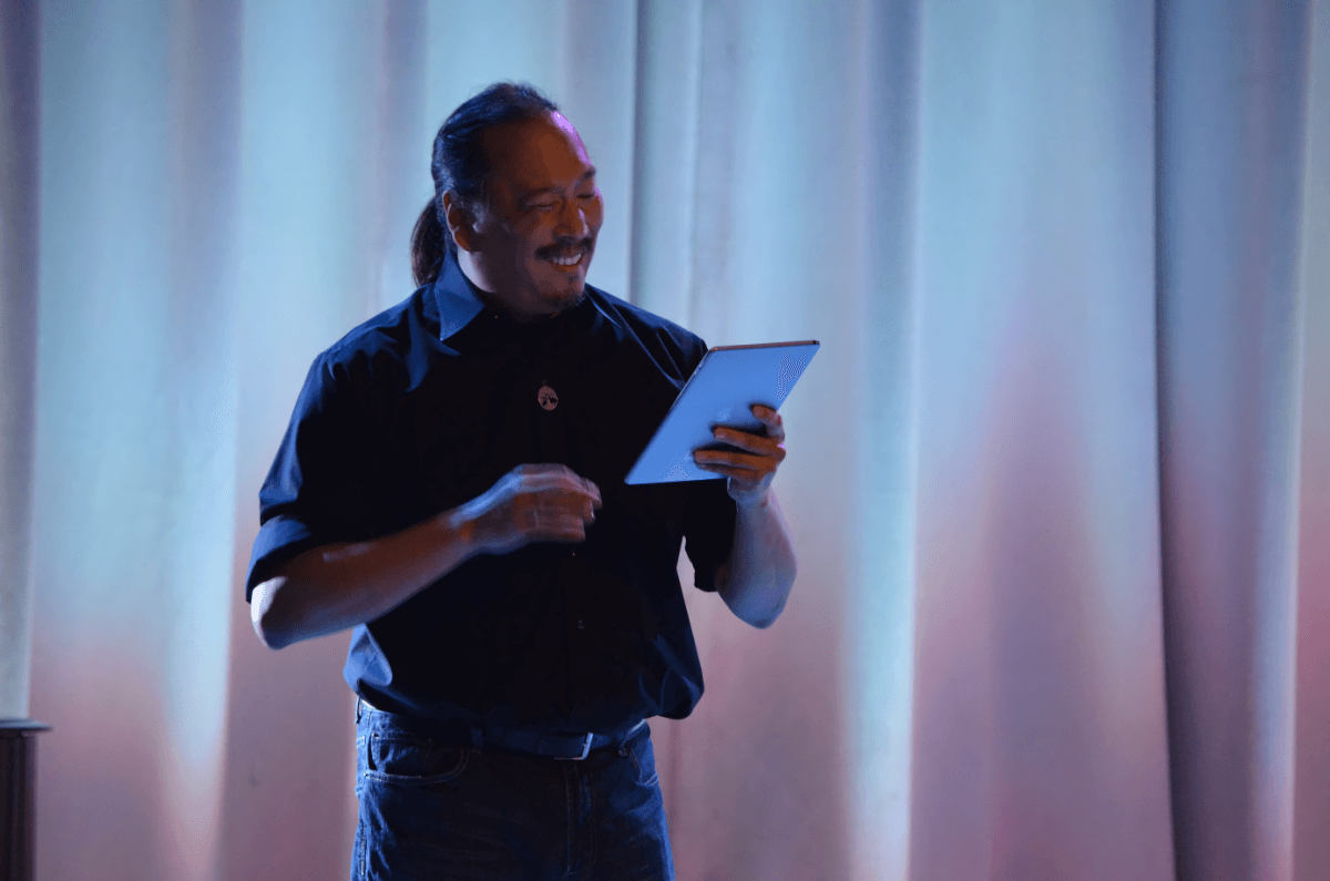 Mendel Lee holding and looking at an iPad in front of a white curtain.