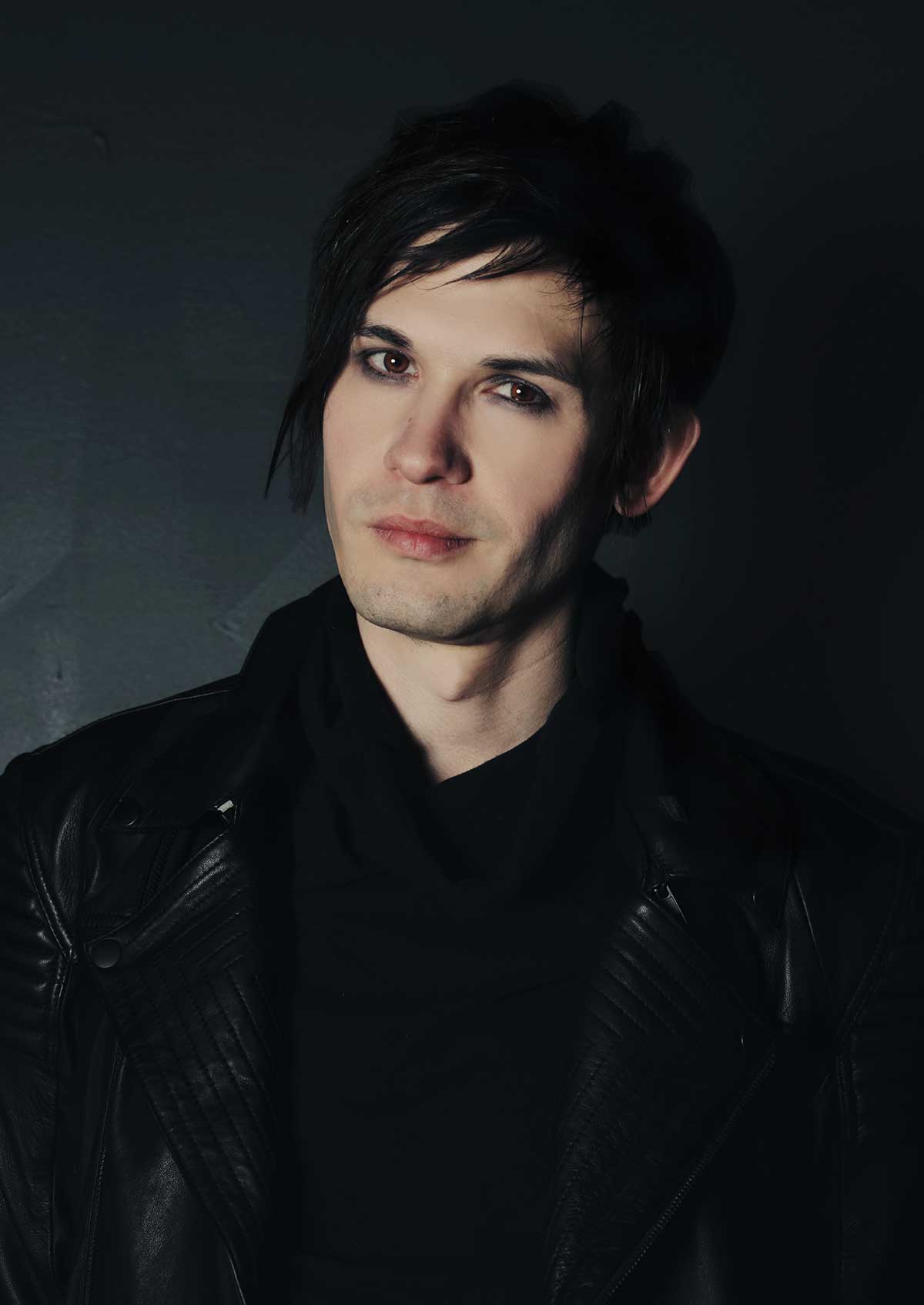 An white-skinned man in a black leather jacket is staring into the camera.