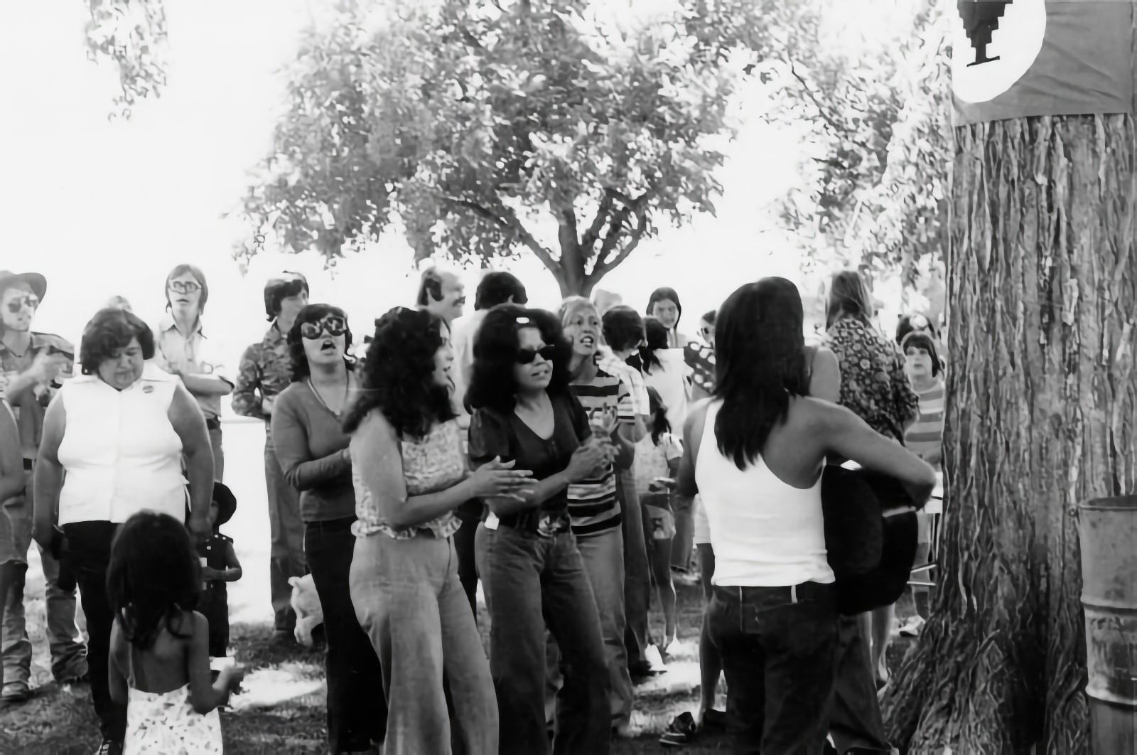 Black and white photo of performers at a public park on a sunny day.
