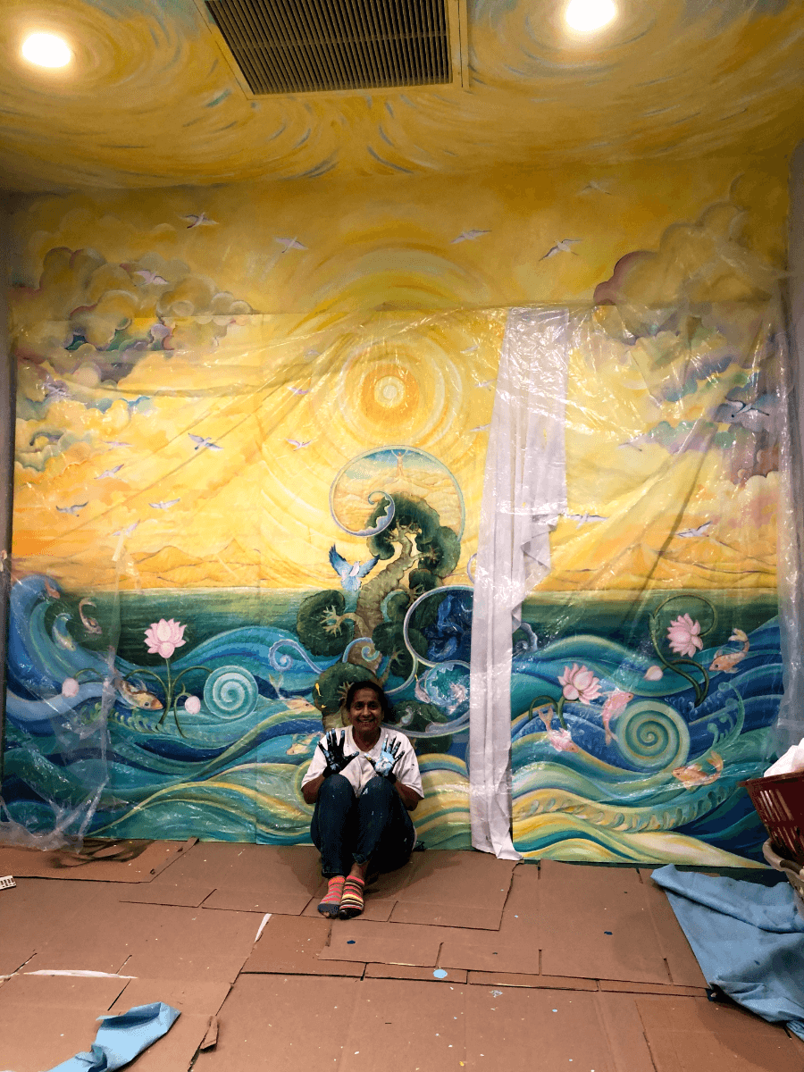 Geeta Dave sits with finished full-room mural.