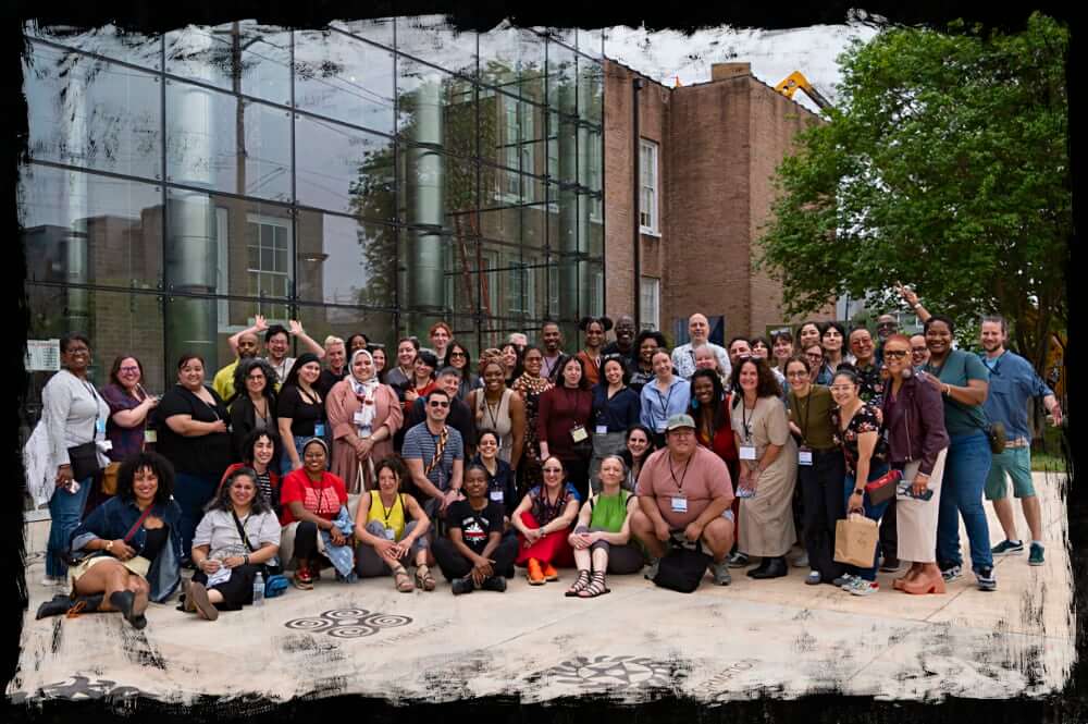 A large group of attendees of the 2025 NPN Partner Meeting stand outdoors and pose for the camera, with people in front sitting down and people on the sides leaning in. Everyone is smiling.